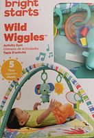 Boxed Bright Starts Wild Wiggles Activity Gym with infant shown playing on gym, highlighting hanging toys and mat.