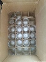 View of 16+ clear pint glasses packed in a cardboard box with individual cardboard dividers for each glass.