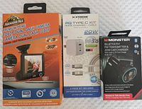 Front view of items in packaging: Armor All dash camera box, Xtreme Power PD Type-C kit, Monster Bluetooth FM transmitter charger