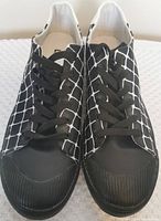 Top-down view of pair of men's black and white patterned casual shoes with black laces and rubber toe caps.