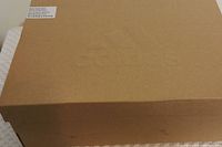 Closed Adidas shoe box in brown cardboard with sizing label on top.