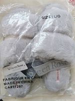 Photo of slippers in original plastic packaging showing the top and footbed plush material, brand tag, and size label L/G.