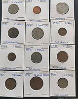Lot of 12 world coins mounted in holders with country, year, and denomination marked.