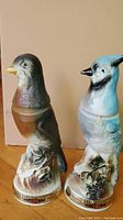 Two collectible bird-shaped decanters by Beams Trophy showing full front and side views with details