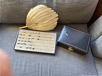 Full view of the feather fan, ring tray with rings, and closed jewelry box showing overall contents and condition.