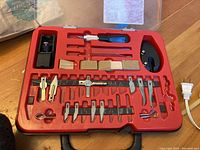Red plastic case open showing hobby carving blades and tools arranged inside with some slots empty