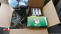 Box with assorted kitchen appliances: electric juicer, manual apple peeler/corer, pasta roller, and drip coffee maker.