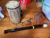 Overview of all instruments including drum, flutes, recorder, spoons and shaker on wooden floor