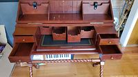 Front view of solid wood cherry stained desk with brass hardware, open compartments, and drawers visible.