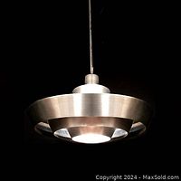 Front view of the pendant light suspended, showing rings and bottom diffuser illuminated