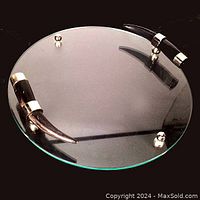 Overhead view of the round glass serving tray showing horn handles and chrome mounts