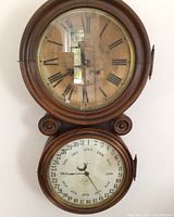Front view showing both time and calendar dials in wooden case