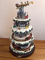 Full view of the multi-tiered ceramic Christmas tree decoration with rotating layers including trains, princesses, and Disneyland Castle with sleigh.