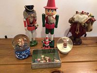 Full view of lot with two nutcrackers, two snow globes, small nativity set, and vintage Santa figure.