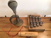 Overview of all items on wooden surface showing squeeze bugle, xylophone, whistles, and metallic chime balls