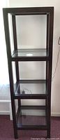 Full view of one dark brown wooden display shelf unit showing four glass shelves and wooden frame