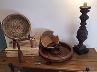 Full lot displayed on wood table showing woven baskets, wood box, pestle and spoon, carved lamp base, and ornaments