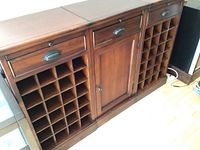 Full front view of the 3-piece wood wine cabinet set, showing two sections with multiple wine bottle storage slots and a middle cabinet with door and drawer above.