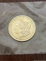Front side of 1885 'O' Morgan Silver Dollar coin in plastic sleeve showing Lady Liberty and date.