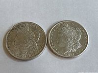 Obverse side of two Morgan silver dollar coins dated 1921 (left) and 1881 (right).