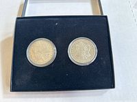 Two Morgan silver dollar coins dated 1921 and 1904 displayed in a black lined box by their protective capsules.