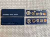 Two 1966 United States Special Mint Sets in blue cases with outer boxes shown on a beige textured surface.