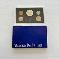 Front view of all five coins in the 1968 US Proof Set in clear plastic case with blue sleeve underneath labeled 'United States Proof Set 1968'