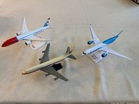 Three model airplanes displayed on a flat surface, showing different airlines.