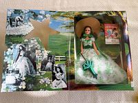 Barbie doll in original box with green and white gown and matching bonnet, accompanying booklet visible in background.