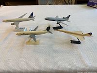 Group of four plastic model airplanes on stands, including British Airways, Alaska Airlines, Continental Airlines, and Concorde.