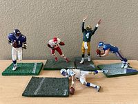 Overview of five NFL McFarlane Toys figurines in action poses each on bases resembling football field turf