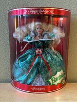 Front view of Happy Holidays Barbie in original shiny red cylindrical box showing doll and packaging detail.