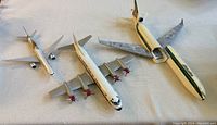 Three model airplanes displayed together on a white surface showing their relative sizes and condition.