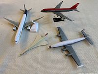 Three small model airplanes from Lufthansa, Northwest Airlines, and a silver unbranded plane, all positioned on a cloth surface.