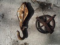 Photo of two antique pulleys laid on concrete surface, showing size, shape, and condition