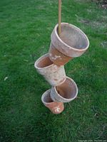 Terracotta pots stacked and tied vertically for hanging or storage, showing wear and buildup on surface.
