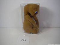 Side view of 7 inch E.T. plush in clear packaging showing profile and shape.