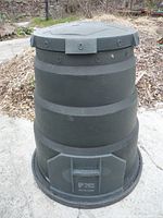 Full view of the dark green plastic compost bin with top lid and ventilation holes