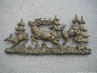 Brass decorative piece showing stag, deer, rabbit, and trees against a plain background.