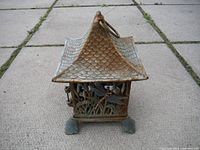 Front view of cast iron garden lantern showing detailed nature and dragonfly cut-out design with patina.
