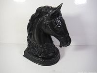 Front side view of black horse head lamp base with visible harness and carved mane.