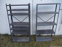 Front view of both metal shelving units side by side against white garage doors, showing overall condition with visible rust and dirt.