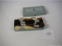 Top view of a blue box labeled Dollfus-Mieg & Cie with embroidery thread skeins in brown, black, cream, and beige colors.