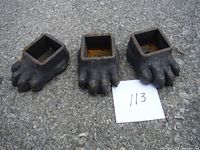 Three cast iron furniture feet shaped like animal paws arranged side by side showing front view with toes.
