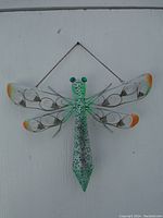 Front view of the metal dragonfly wall hanging showing detailed wing patterns and coloration.