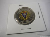 Photo of the front side of the Canadian two-dollar coin showing the colorful "Victory" V emblem with a torch symbol and inscriptions.