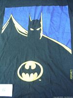Close-up photo of the large Batman graphic print on the black T-shirt, showing Batman's silhouette and yellow emblem.