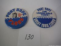 Two vintage commemorative buttons side-by-side on white background, one blue and one white, referencing Port Hope Flood in 1980.
