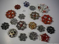 Top view of 18 vintage valve handles of various colors and sizes arranged on white surface.