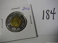 Close-up of the coin's obverse showing a sailing ship and year 2012 in a protective holder.